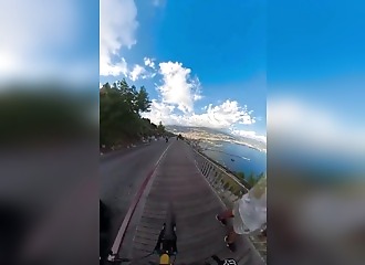 He wheelies his bike right in the middle of a downhill stretch on the sidewalk—pedestrians can't believe their eyes